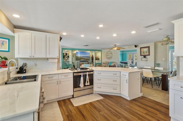 kitchen featuring white cabinets, kitchen peninsula, sink, and electric range