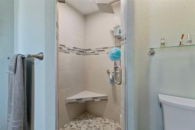 bathroom with toilet and a shower with door