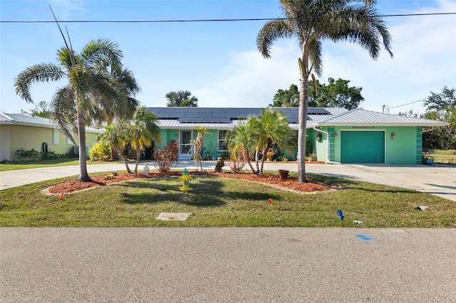 ranch-style house with a garage, a front yard, and solar panels