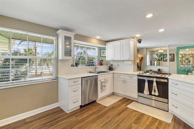 kitchen with sink, white cabinetry, dark hardwood / wood-style flooring, stainless steel appliances, and decorative backsplash