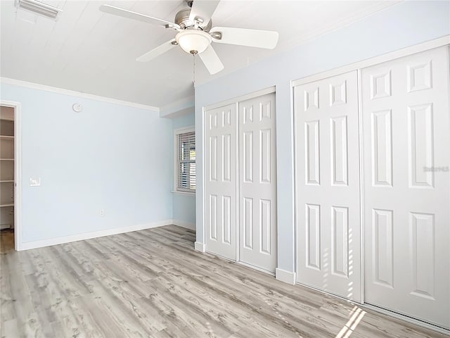 unfurnished bedroom with multiple closets, ceiling fan, crown molding, and light wood-type flooring