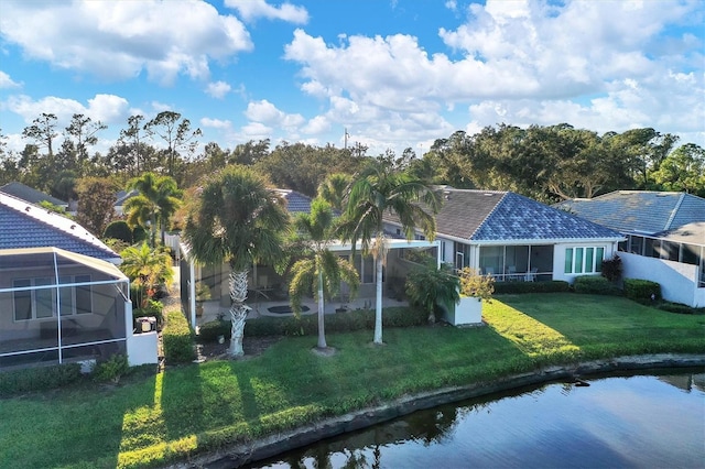 back of property featuring a water view, glass enclosure, and a lawn