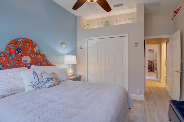 bedroom with light hardwood / wood-style flooring, a closet, ceiling fan, and a high ceiling