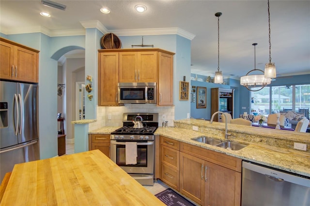 kitchen featuring sink, appliances with stainless steel finishes, kitchen peninsula, pendant lighting, and decorative backsplash