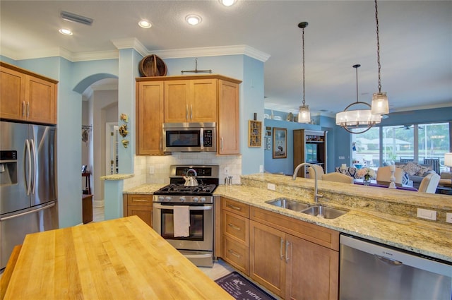 kitchen featuring butcher block counters, sink, pendant lighting, stainless steel appliances, and backsplash