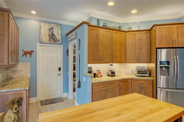 kitchen featuring backsplash, ornamental molding, stainless steel fridge with ice dispenser, light stone countertops, and light wood-type flooring