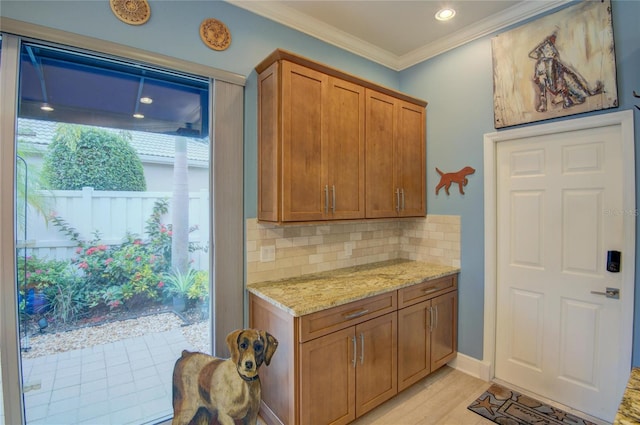 kitchen with light stone counters, crown molding, light hardwood / wood-style floors, and tasteful backsplash