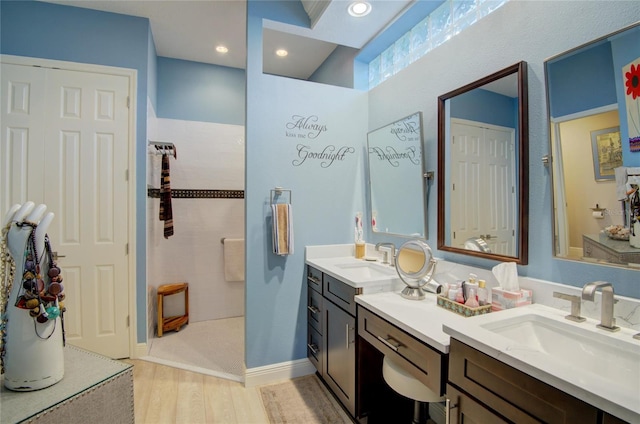 bathroom with hardwood / wood-style flooring, vanity, and a tile shower