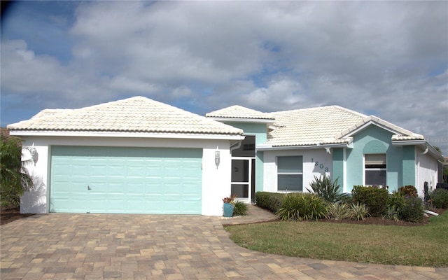 ranch-style home with a garage, decorative driveway, a tile roof, and stucco siding