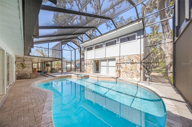 view of pool with glass enclosure, a pool with connected hot tub, and a patio area