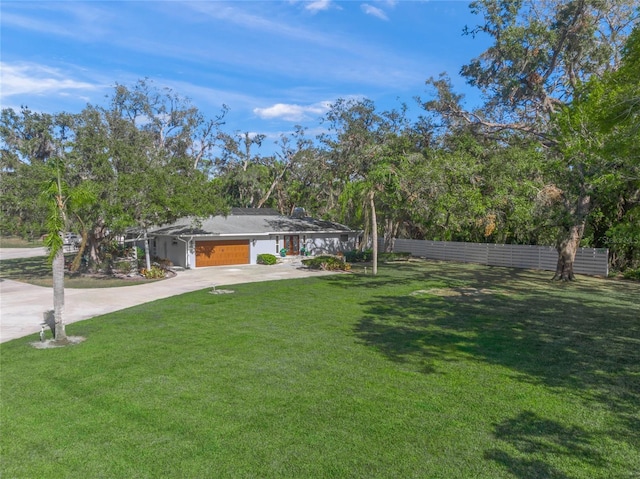 view of yard featuring fence and concrete driveway