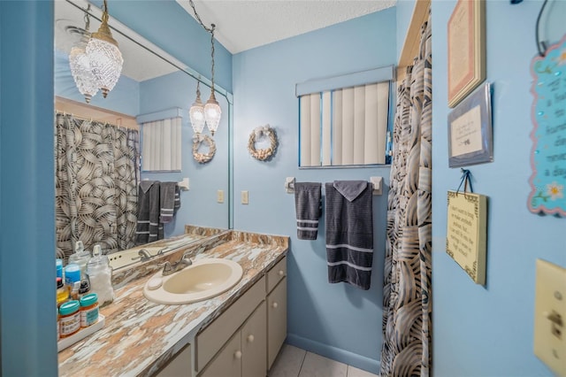 bathroom with tile patterned flooring, baseboards, a textured ceiling, and vanity