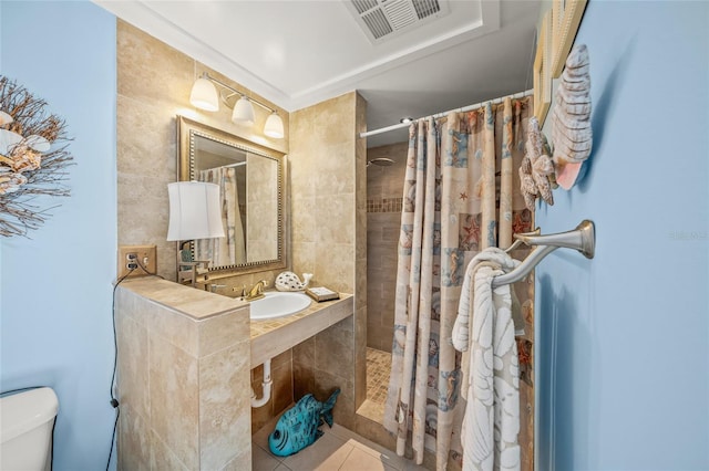 full bathroom with tile patterned flooring, toilet, a sink, visible vents, and tiled shower