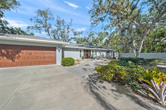 view of front of home featuring a garage, concrete driveway, fence, and stucco siding