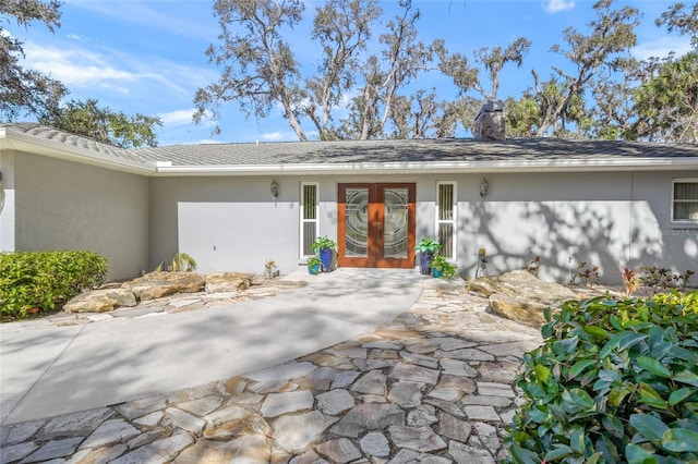 exterior space with stucco siding, a chimney, and french doors