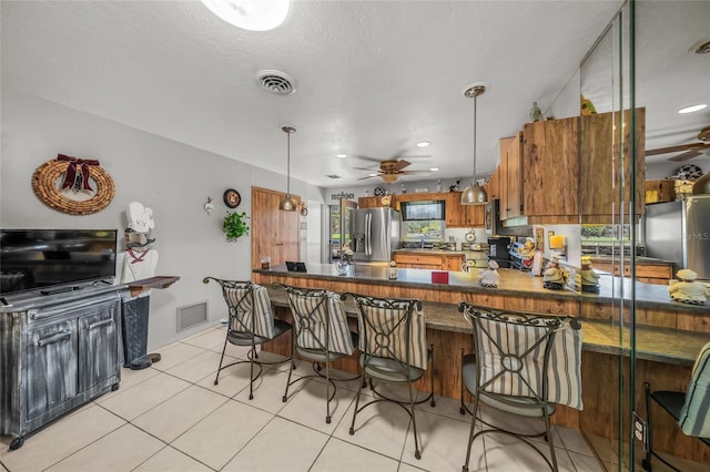 kitchen with a peninsula, visible vents, stainless steel refrigerator with ice dispenser, and decorative light fixtures