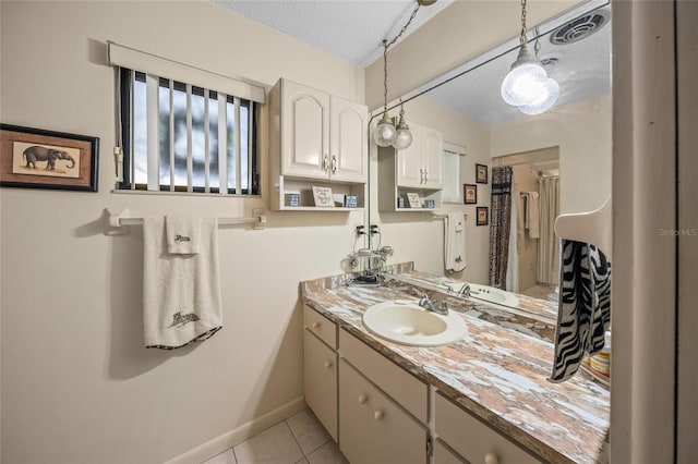 bathroom featuring visible vents, a textured ceiling, vanity, baseboards, and tile patterned floors