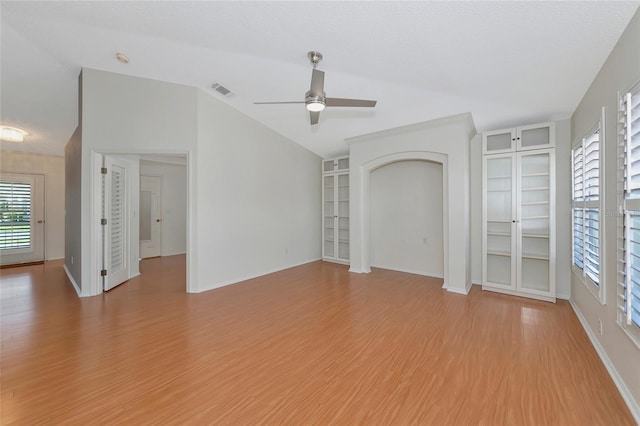 interior space featuring lofted ceiling, ceiling fan, a textured ceiling, built in shelves, and light wood-type flooring