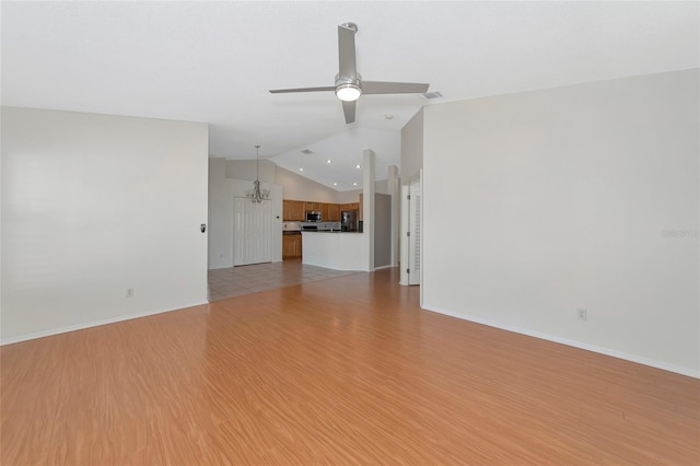 unfurnished living room with vaulted ceiling, ceiling fan with notable chandelier, and light hardwood / wood-style flooring