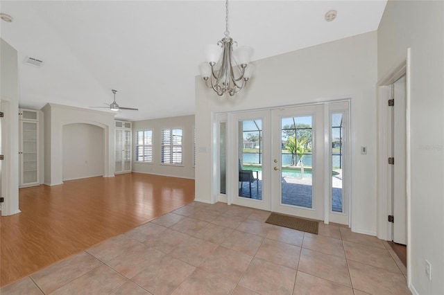 tiled foyer entrance featuring french doors and ceiling fan with notable chandelier