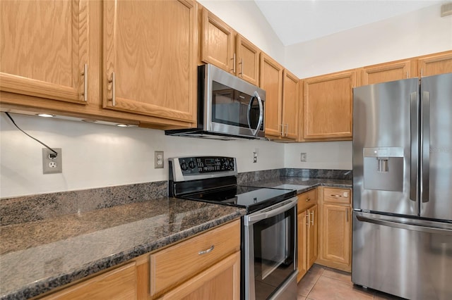 kitchen featuring dark stone countertops, light tile patterned floors, and appliances with stainless steel finishes