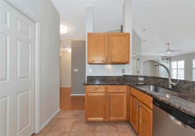 kitchen with light tile patterned flooring, sink, stainless steel dishwasher, and dark stone counters