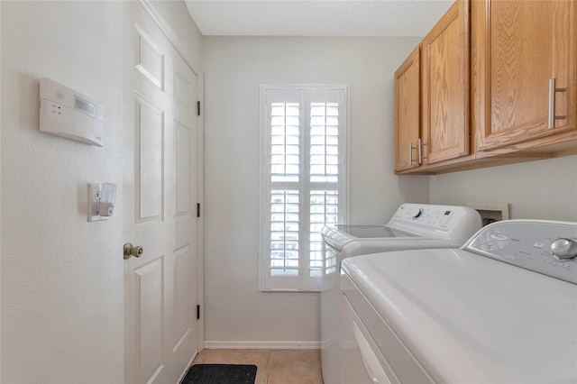 laundry area featuring cabinets, light tile patterned floors, a wealth of natural light, and independent washer and dryer