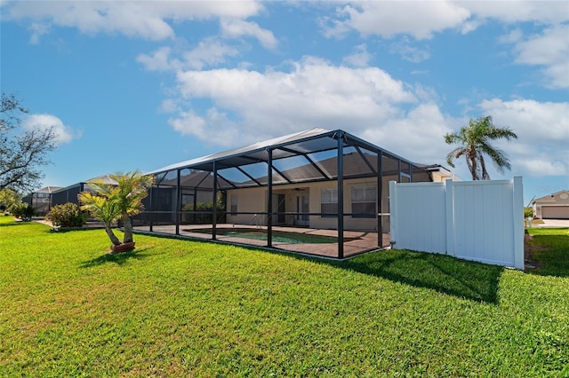 rear view of property featuring a yard, a patio, and glass enclosure