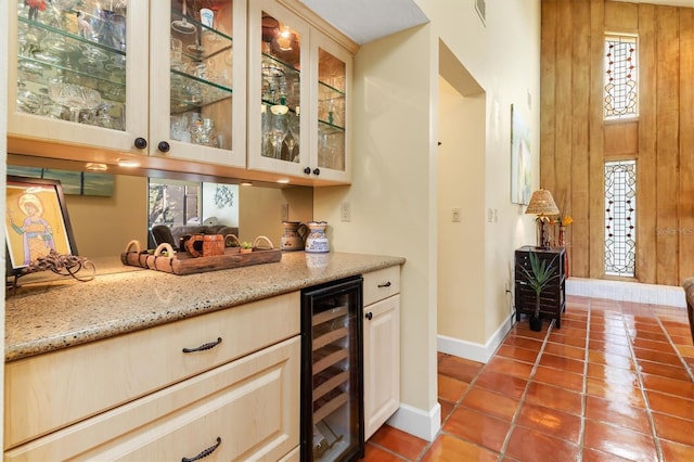 bar with light stone counters, beverage cooler, and tile patterned floors