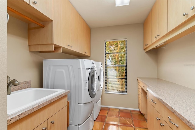 washroom featuring sink, light tile patterned floors, washing machine and dryer, and cabinets