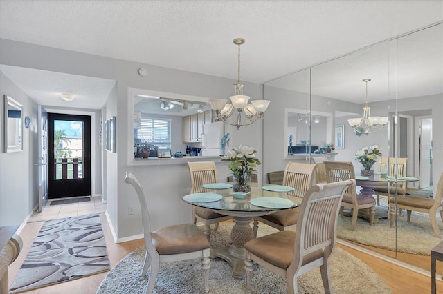 dining space with a notable chandelier, light hardwood / wood-style flooring, and a textured ceiling