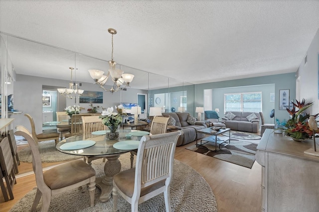 dining area featuring an inviting chandelier, light hardwood / wood-style flooring, and a textured ceiling