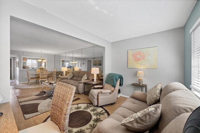 living room featuring a textured ceiling, a notable chandelier, and light hardwood / wood-style floors