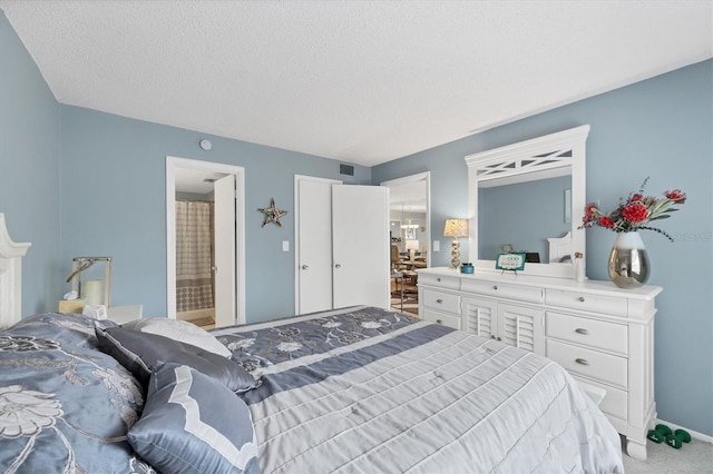 bedroom featuring ensuite bath, carpet floors, and a textured ceiling