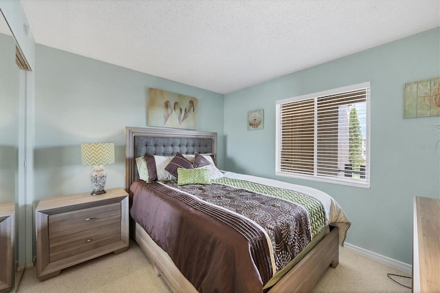 bedroom with light colored carpet and a textured ceiling