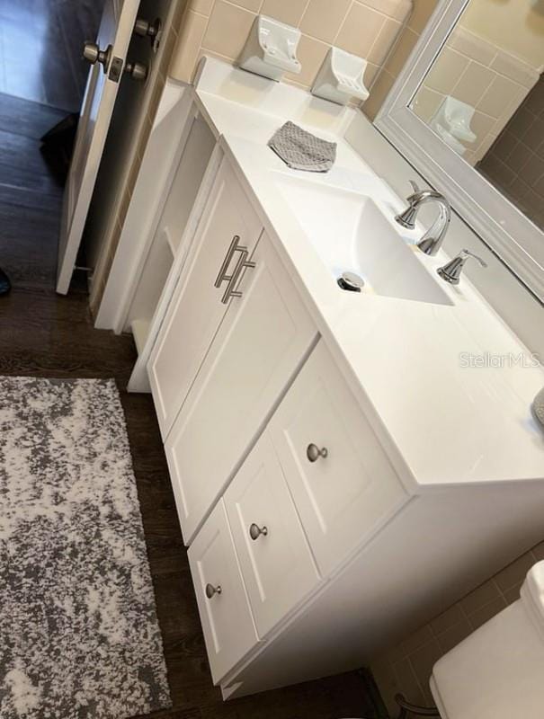 bathroom featuring hardwood / wood-style flooring, vanity, toilet, and decorative backsplash