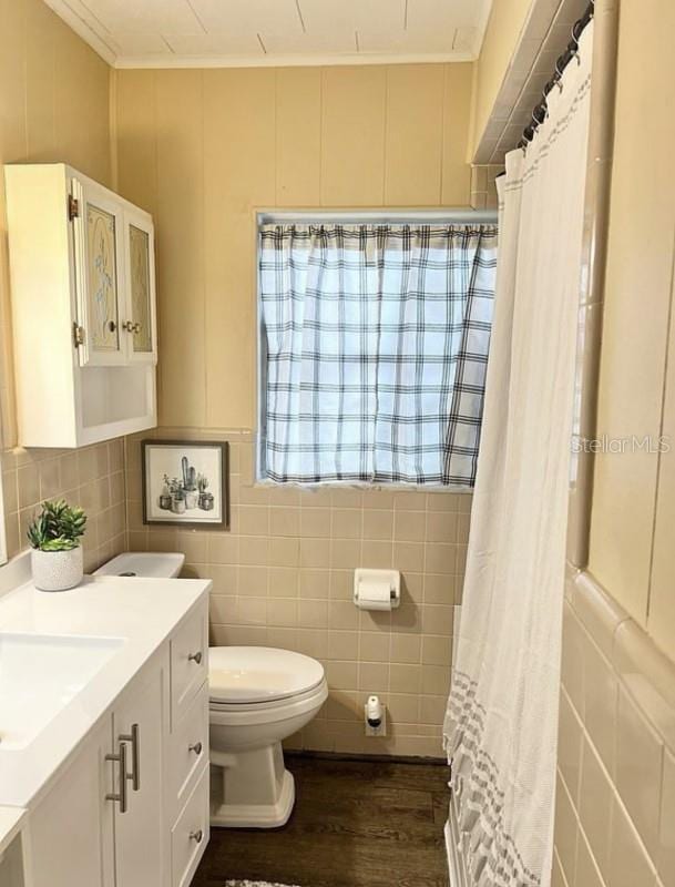 bathroom with toilet, tile walls, ornamental molding, vanity, and hardwood / wood-style floors