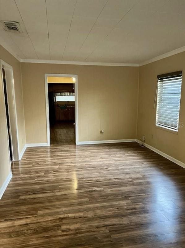 empty room with crown molding and dark wood-type flooring