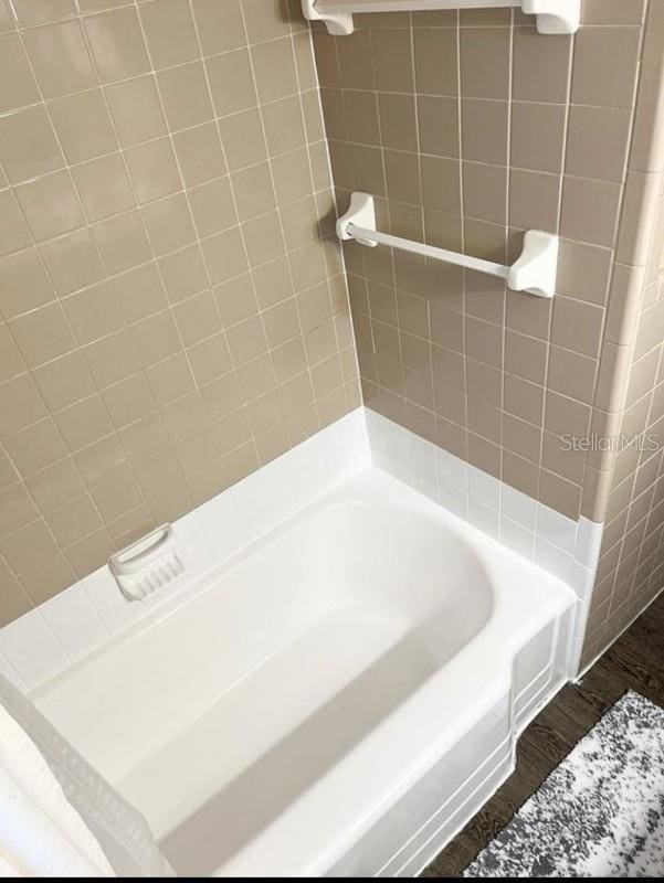 bathroom with hardwood / wood-style flooring and tiled shower / bath