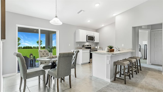 kitchen featuring appliances with stainless steel finishes, decorative light fixtures, a breakfast bar area, white cabinets, and kitchen peninsula