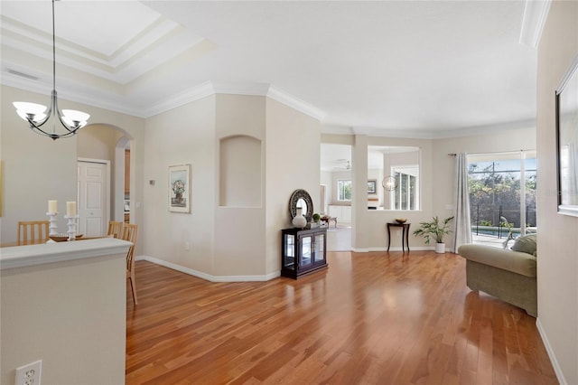 interior space featuring a notable chandelier, wood-type flooring, ornamental molding, and a healthy amount of sunlight