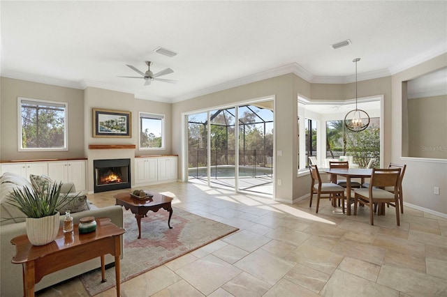 living room featuring crown molding, ceiling fan with notable chandelier, and a healthy amount of sunlight