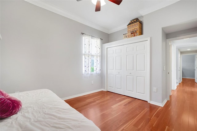 bedroom with crown molding, hardwood / wood-style floors, ceiling fan, and a closet