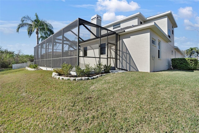 rear view of house with a lanai and a lawn