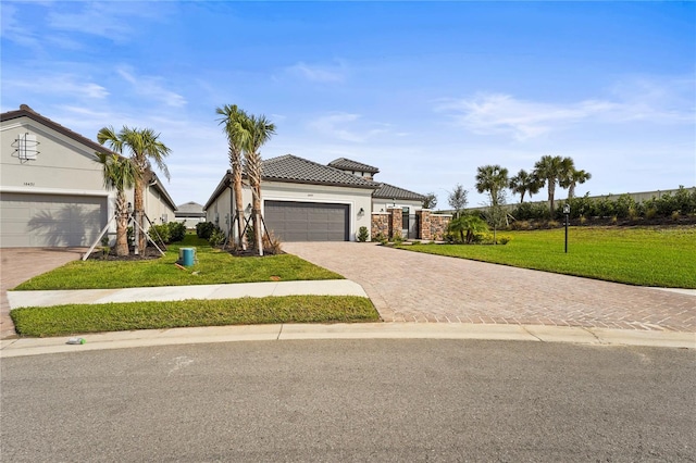 view of front of property with a garage, a tiled roof, decorative driveway, stucco siding, and a front lawn