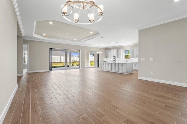 unfurnished living room featuring crown molding, light wood-style flooring, and an inviting chandelier