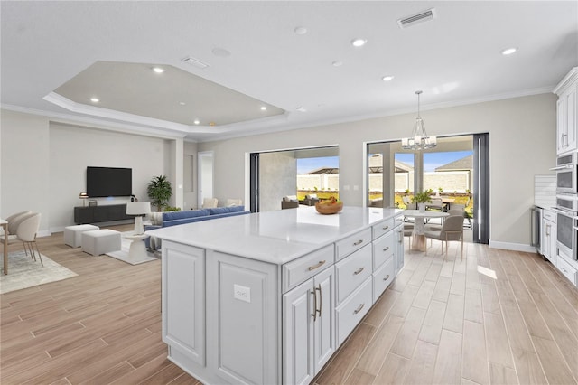 kitchen featuring light countertops, open floor plan, white cabinets, and a kitchen island