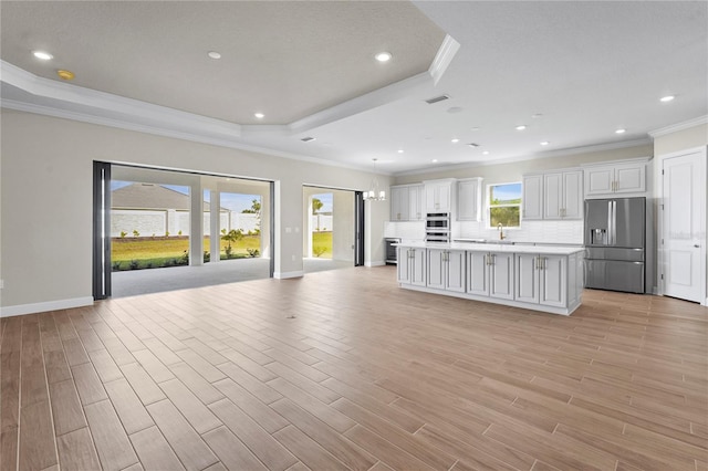 unfurnished living room featuring baseboards, ornamental molding, a raised ceiling, and light wood-style floors