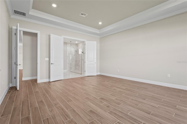 unfurnished bedroom with wood finish floors, a tray ceiling, visible vents, ornamental molding, and baseboards