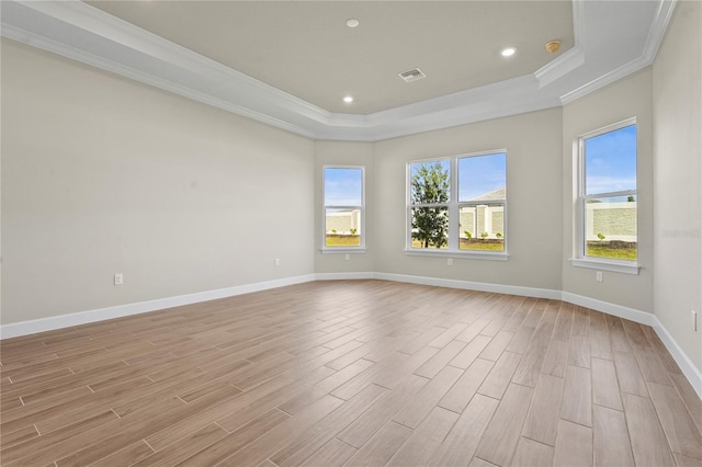 unfurnished room featuring light wood-type flooring, baseboards, a raised ceiling, and ornamental molding